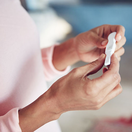 woman wearing pink sweater waiting for pregnancy test results